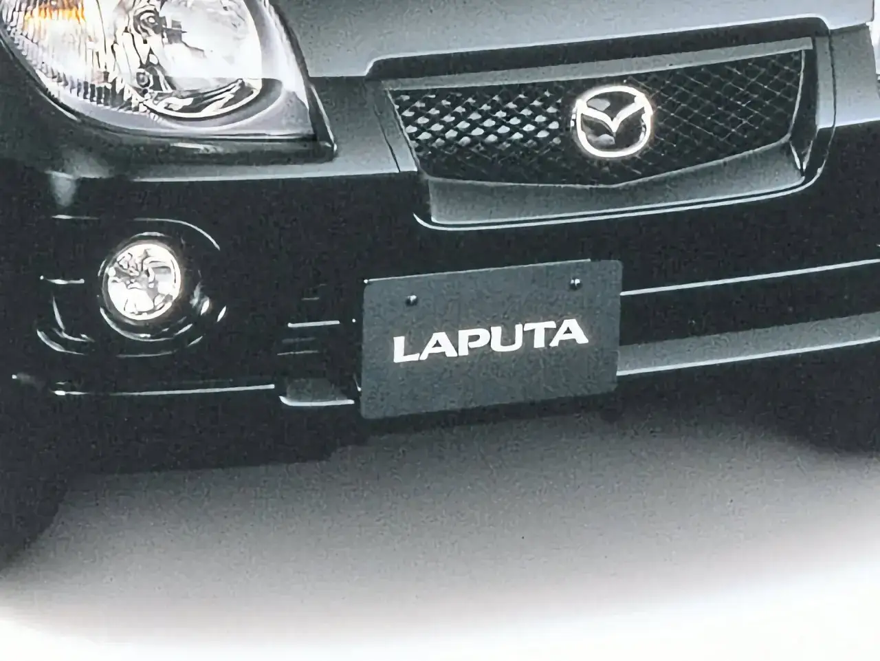 Czarne auto z logo Mazdy i napisem 
