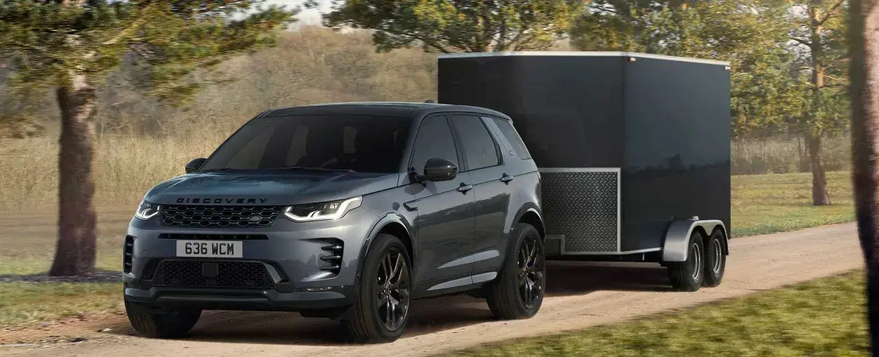 Szare Discovery Sport z przyczepą kempingową na drodze. Idealne auto do przyczepy kempingowej? Ten model sprawdzi się w każdej sytuacji.