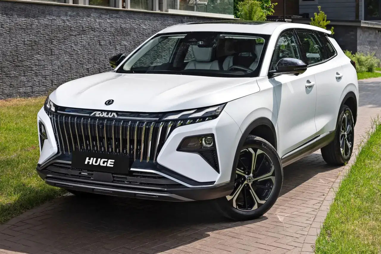 Nowy chiński SUV Aeolus z imponującym grillem i nowoczesnymi światłami, zaparkowany na podjeździe z kostki brukowej.