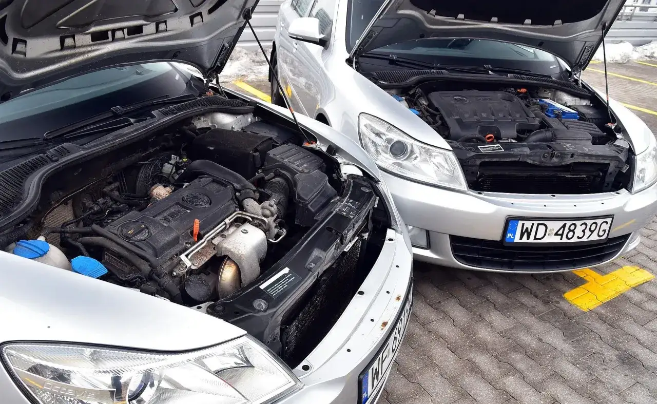Dwa srebrne samochody z otwartymi maskami, silniki gotowe do pracy. Który wybierzesz: diesel czy benzyna?