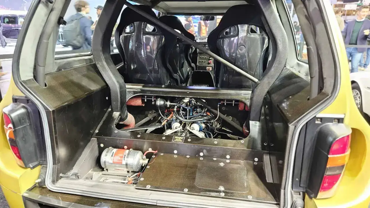 Widok na potężny silnik V10 z tyłu Renault Espace F1, otoczony klatką bezpieczeństwa i kubełkowymi fotelami.