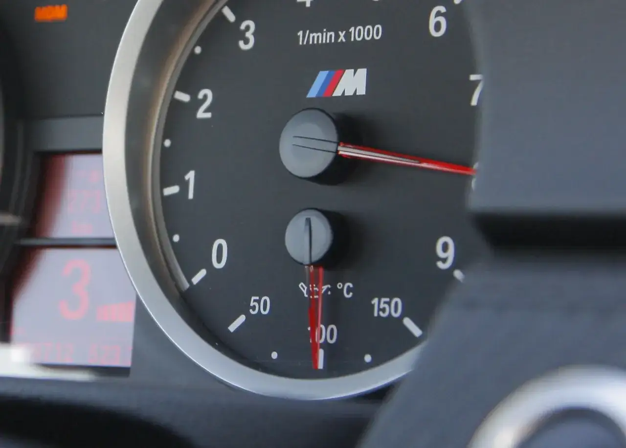 Wskaźnik kontrolki temperatury oleju w BMW M pokazuje 100°C. Obok obrotomierz.