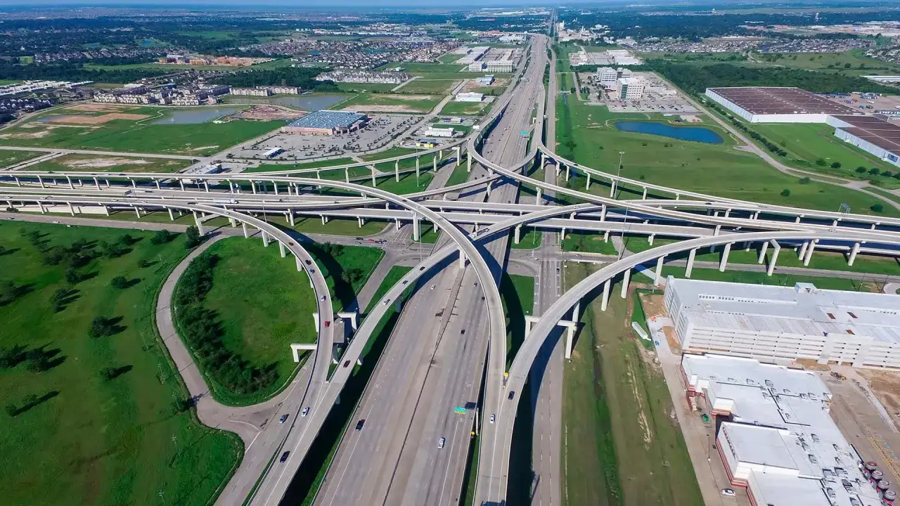 Rozległy węzeł autostradowy, przypominający najszerszą autostradę na świecie, z wieloma pasami ruchu i wiaduktami przecinającymi się w powietrzu.