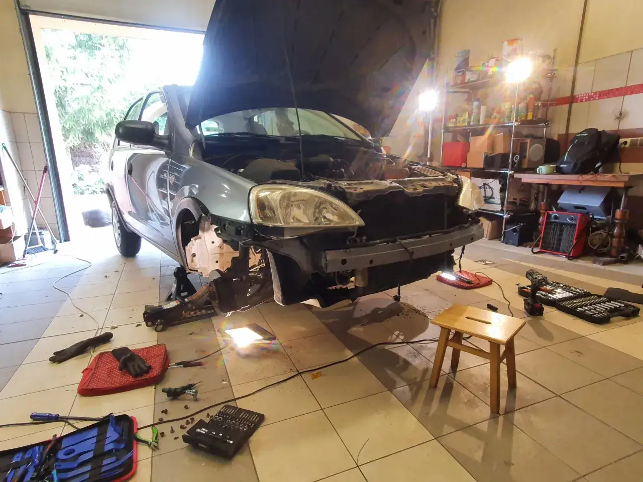 Warsztat samochodowy, auto na podnośniku, w trakcie montażu czujników parkowania. Narzędzia i sprzęt na podłodze.