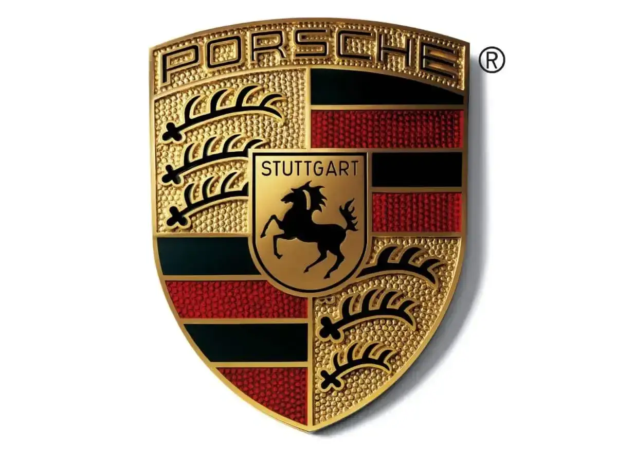 Złote logo Porsche, symbol luksusowych marek samochodów, z herbem Stuttgartu i czarnym koniem.