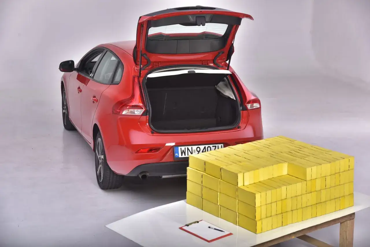 Czerwony hatchback z otwartym bagażnikiem obok sterty ż&oacute;łtych cegieł. Czy zmieści się wszystko, co potrzebne, jak w sedanie?