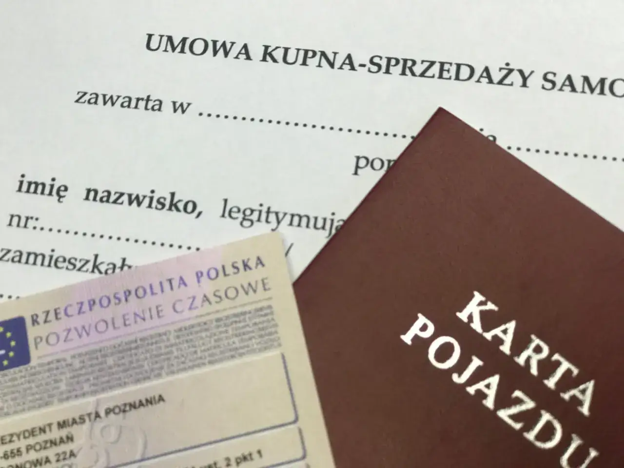 Umowa kupna-sprzedaży samochodu z wyłączeniem rękojmi, obok karta pojazdu i pozwolenie czasowe.