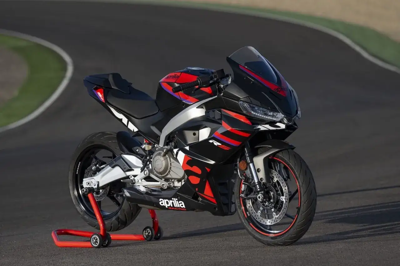Czarny motocykl Aprilia RS 660 na czerwonym stojaku na torze wyścigowym. Koncesja na A2 jest ważna, więc można śmiało jeździć!