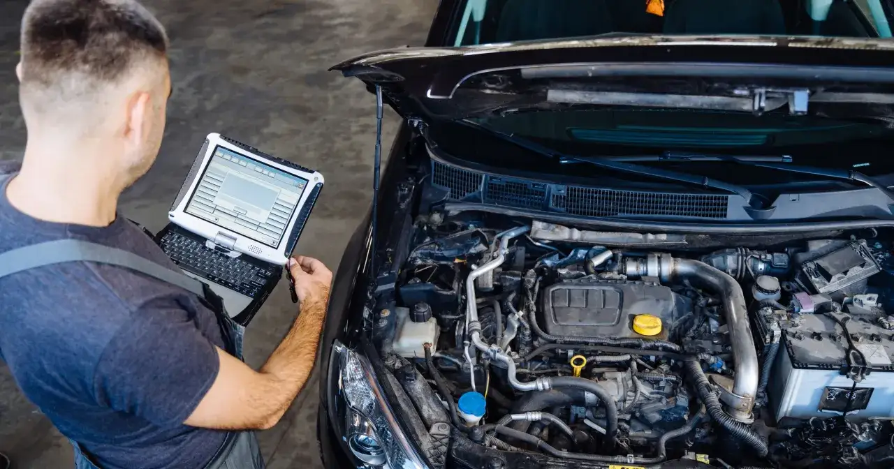 Mechanik diagnozuje silnik benzynowy, który może być jednym z najgorszych. Na ekranie komputera diagnostycznego widać dane techniczne.