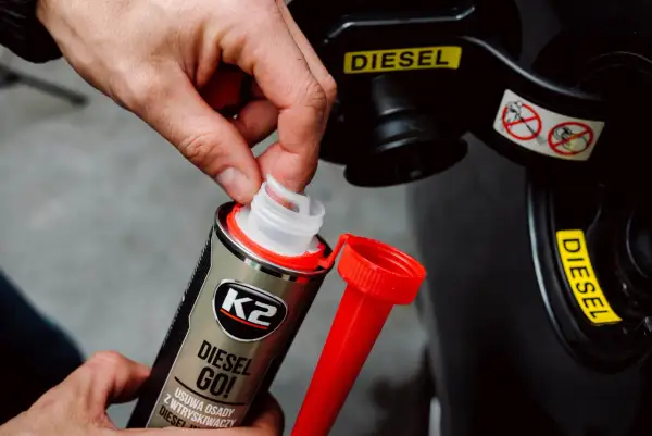 Dłoń otwiera dodatek do paliwa K2 Diesel Go!, który pomaga zapobiegać zamarzaniu diesla. Wskaźnik "DIESEL" na klapce wlewu.