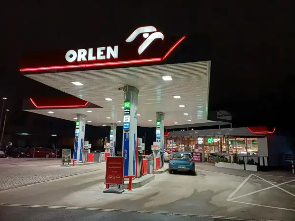 Nocna stacja Orlen z podświetlanym logo. Samochód czeka na tankowanie, bo kiedy tańsze paliwo, warto zatankować.