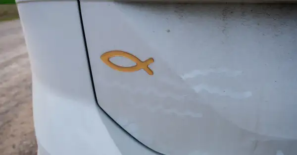Złoty symbol ryby na białym samochodzie. To chrześcijański znak, który oznacza "Jezus Chrystus, Syn Boży, Zbawiciel".
