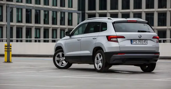 Srebrny Skoda Karoq, jeden z najmniej awaryjnych aut segmentu B, parkuje przed nowoczesnym budynkiem.