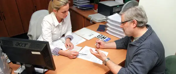 Mężczyzna z okularami i kobieta przy biurku analizują dokumenty, szukając rozwiązania problemu: błąd w CEPIK jak skorygować.