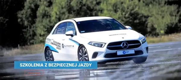 Biały Mercedes na mokrym torze w Poznaniu, ćwiczący bezpieczną jazdę. Szkolenia z bezpiecznej jazdy.