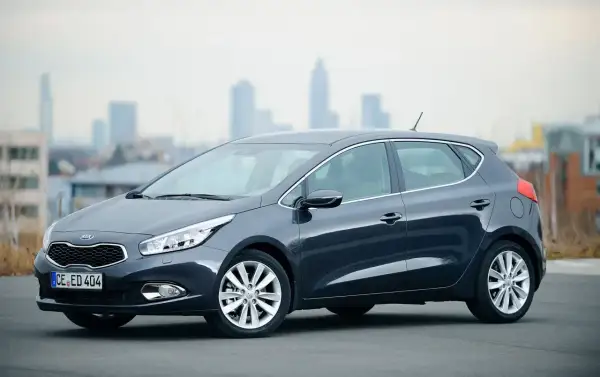 Szary Kia Ceed 1.6 GDI, zgrabny hatchback na tle miasta. Czy są jakieś wady?