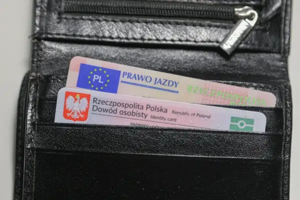 Czarny portfel z polskim dowodem osobistym i prawem jazdy. Na dokumencie prawa jazdy widnieje napis "PRAWO JAZDY" oraz symbol PL.