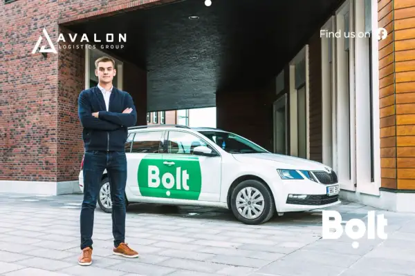 Młody mężczyzna stoi obok białego samochodu z logo Bolt. Zastanawiasz się, ile można zarobić na Bolcie?