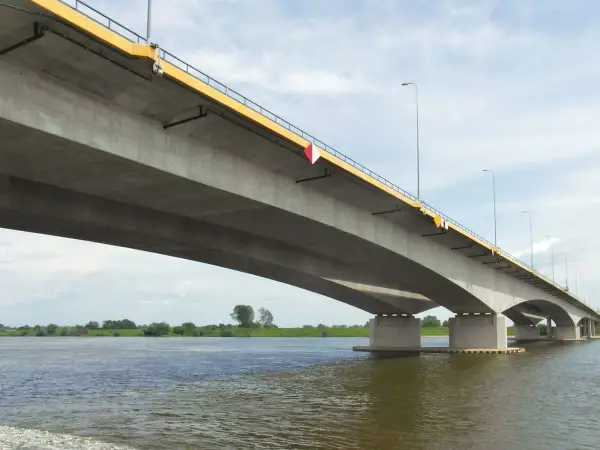 Betonowy most, najdłuższy w Polsce, rozciąga się nad szeroką rzeką, łącząc brzegi w słoneczny dzień.