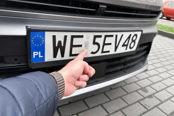 Palec wskazuje hologram na polskiej tablicy rejestracyjnej. Zastanawiasz się, ile czasu na rejestracje auta z zagranicy?
