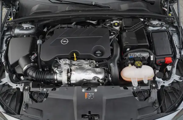 Silnik samochodu Opel z logo marki. Pod maską widać turbosprężarkę i zbiornik płynu chłodniczego. To silnik CDTI, co to znaczy? To silnik Diesla z turbodoładowaniem.