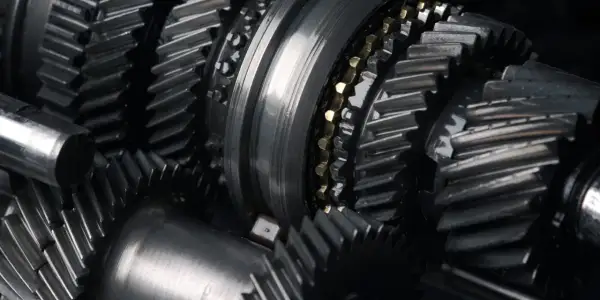 Zbliżenie na metalowe koła zębate, sugerujące awarię skrzyni biegów. Widoczne elementy mechanizmu, gotowe do naprawy.
